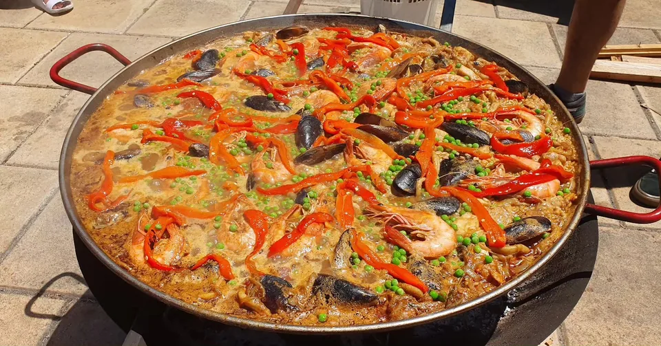 A large seafood paella pan with prawns, mussels, peas and red peppers